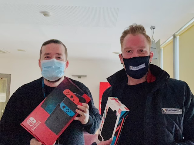 Two People In Facemasks Hold Nintendo Switch Boxes