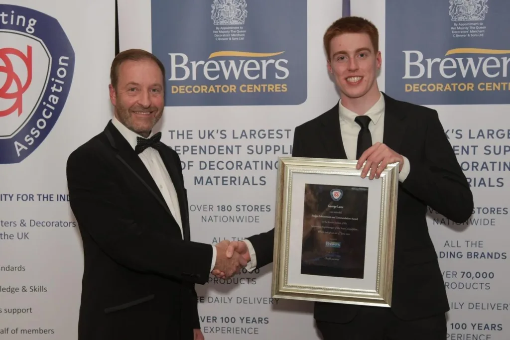 George Lane Receiving A Painting And Decorating Association Framed Certificate From A Male Judge