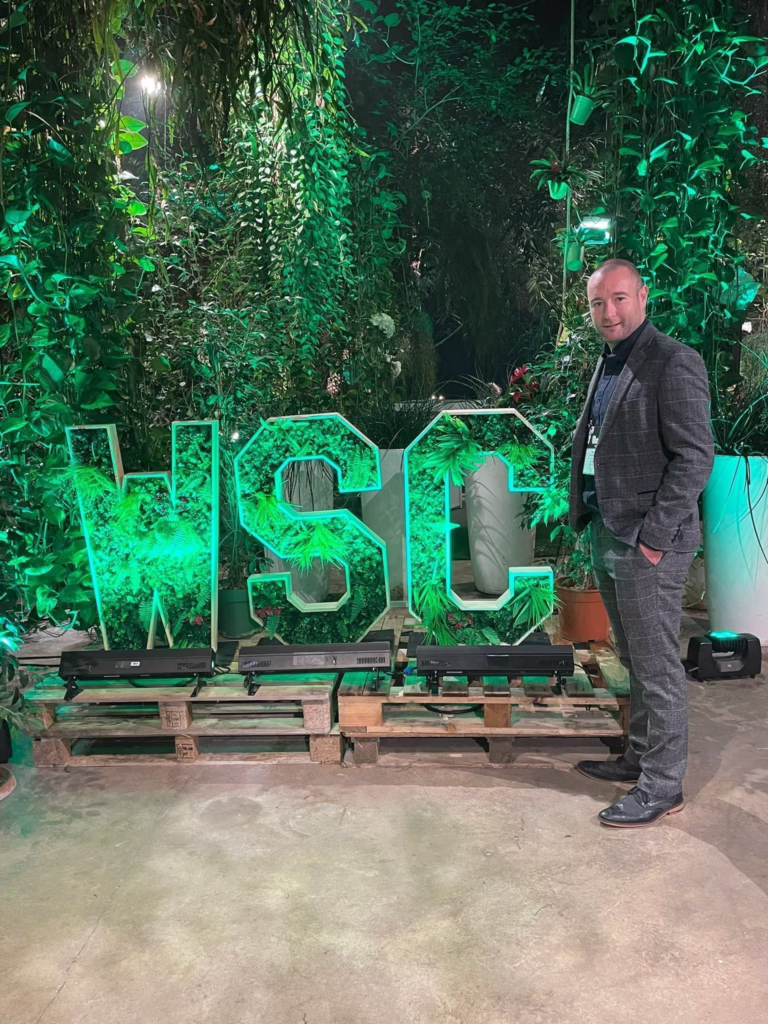 Person beside illuminated green letters WSC
